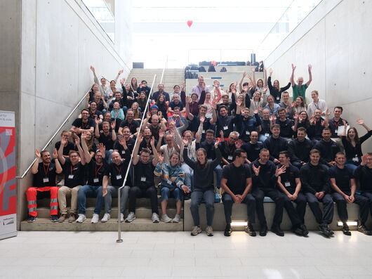 Eine große Gruppe Menschen sitzt auf einer Treppe und jubelt
