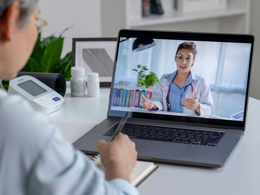Laptop mit Übertragung einer Ärztin im weißen Kittel.