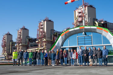 Gruppenbild mit Personen, die in einer Reihe auf dem Hubschrauberlandeplatz der Uniklinik RWTH Aachen stehen. Im Hintergrund ist die Uniklinik und der Eingang zur zentralen Notaufnahme auf dem Landeplatz zu sehen.