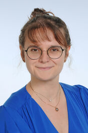 Dr. med. Christiane Licht Porträtfoto einer Frau mit braunem Haar, Zopf und Brille, die ein blaues Oberteil trägt und freundlich in die Kamera lächelt.